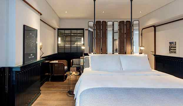 Modernt hotellrum med stor dubbelsäng och sittgrupp i bakgrunden. (AI-genererad text)