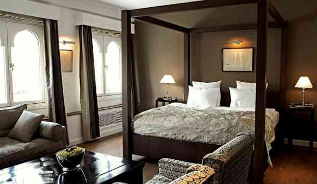 Ett sovrum med en säng med himmelssäng, sittmöbler och bord. (AI-genererad text)