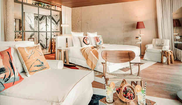 Ett modernt inrett sovrum med stora fönster, ljusa möbler och dekorativa kuddar. (AI-genererad text)