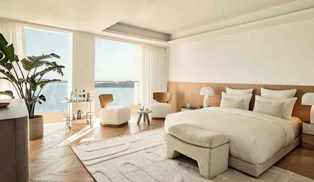 Modernt sovrum med utsikt över havet. Inredning i ljusa färger. Stort fönster med havsutsikt. (AI-genererad text)