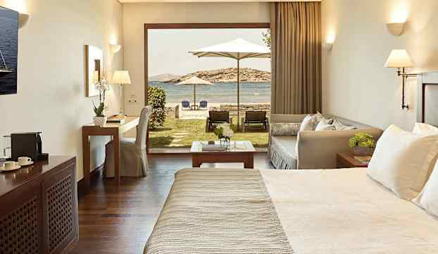 Inredning i hotellrum med direkt utgång till trädgård och havsutsikt. (AI-genererad text)