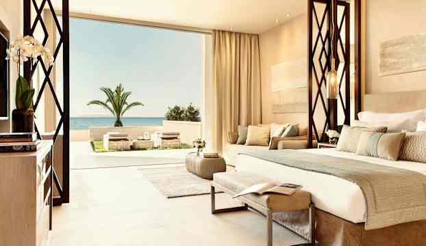 Lyxigt hotellrum med utsikt över havet och en palm på terrassen. (AI-genererad text)