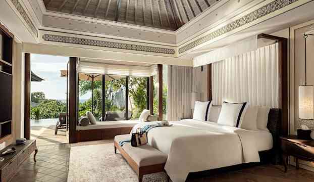 Lyxigt hotellrum med stor säng, fönster mot terrass och utomhuspool. (AI-genererad text)