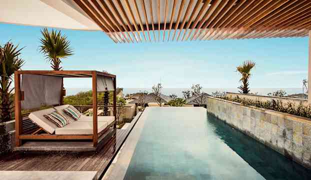 Utsikt över en infinitypool och en liggsoffa vid ett strandnära område. (AI-genererad text)