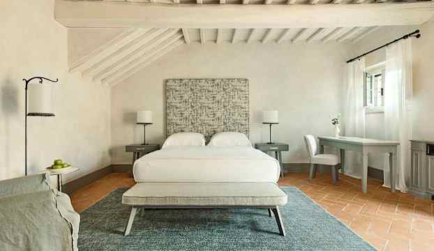 Ett ljust sovrum med en dubbelsäng, två nattduksbord med lampor, ett skrivbord med stol och ett fönster med vita gardiner. (AI-genererad text)