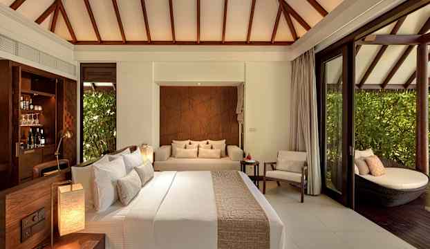 Ett elegant hotelrum med säng, soffa och direktaccess till en sittgrupp utomhus. (AI-genererad text)