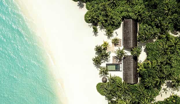 Fågelperspektiv av en tropisk strand med vita sandstränder, turkost vatten och gröna palmer. (AI-genererad text)