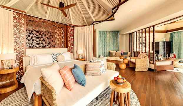 Ett rymligt sovrum med trädetaljer, säng och sittgrupp. (AI-genererad text)