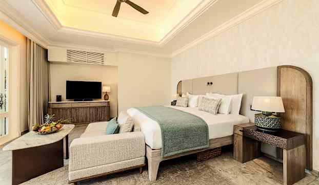 Ett hotellrum med en dubbelsäng, fåtölj, soffbord och en tv. (AI-genererad text)