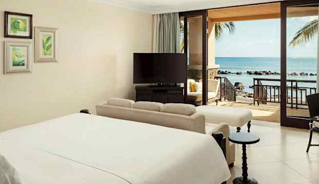 Hotellrum med havsutsikt och stor säng. (AI-genererad text)