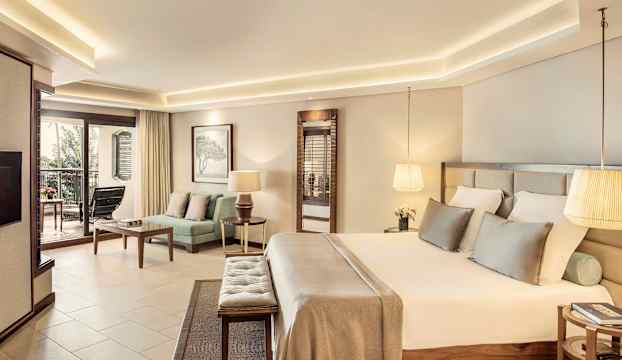 Ett elegant hotellrum med en stor säng och sittgrupp, samt en balkong med utsikt. (AI-genererad text)