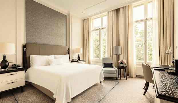 Ett hotellrum med en dubbelsäng och stora fönster. (AI-genererad text)