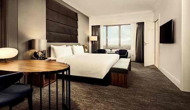 Ett modernt hotellrum med en stor säng, skrivbord och fönster. (AI-genererad text)