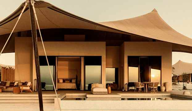 En modern byggnad med glastak, möbler utomhus och en liten pool. (AI-genererad text)