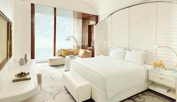 Modernt hotellrum med havsutsikt, vit inredning och stora fönster. (AI-genererad text)