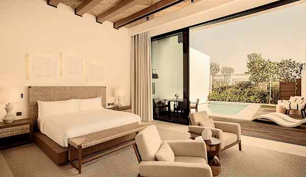 Hotellrum med dubbelsäng, sittmöbler och utsikt mot en privat pool. (AI-genererad text)