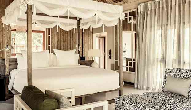 Interiör av ett rum med en himmelssäng och vardagsrumsområde. (AI-genererad text)