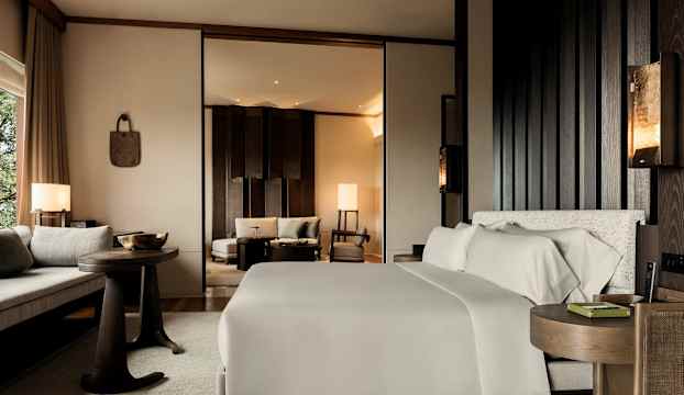 Ett modernt hotellrum med en dubbelsäng, sittområde och stor spegel. (AI-genererad text)