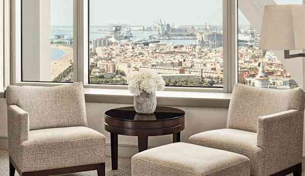 Ett modernt vardagsrum med utsikt över en stad och hamn. (AI-genererad text)