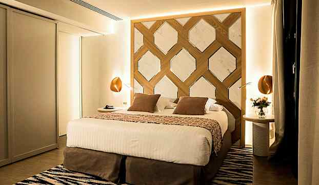 En modern dubbelsäng med dekorativ huvudgavel i ett välbelyst sovrum. (AI-genererad text)