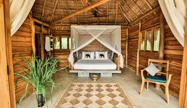 Ett rum med en säng med baldakin i en rustik träbyggnad. (AI-genererad text)