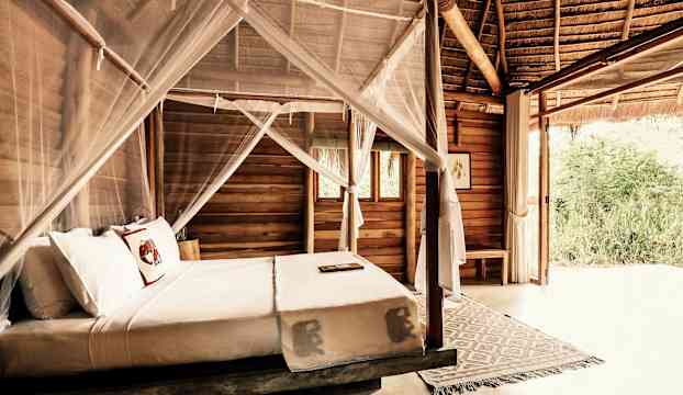 Inbäddad träsäng med myggnät i ett rustikt sovrum. (AI-genererad text)