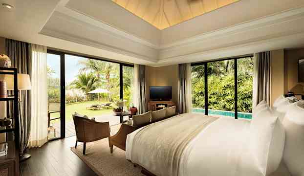 Ett lyxigt sovrum med stora fönster som vetter mot ett grönt trädgårdsområde med palmer. (AI-genererad text)