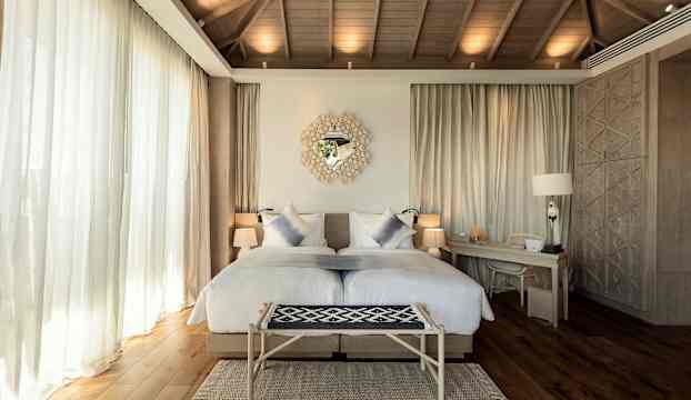 Bild av ett ljus och elegant hotellrum med en dubbelsäng, skrivbord och dekorativa detaljer. (AI-genererad text)