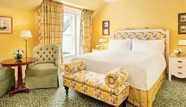 Ett sovrum med gul inredning, en stor säng, och sittmöbler. (AI-genererad text)