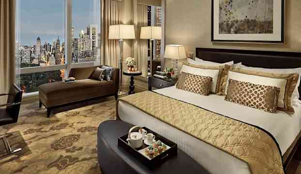 Ett lyxigt hotellrum med stor säng och panoramautsikt över en stad. (AI-genererad text)