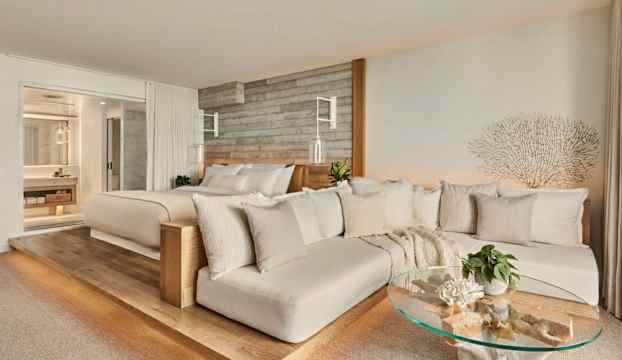 Bild på ett ljus och modernt hotellrum med en dubbelsäng, soffmöbler och ett glasbord. (AI-genererad text)