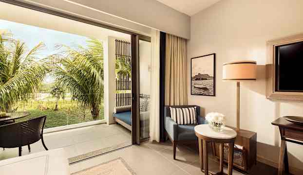 Hotellrum med uteplats och utsikt mot en grönskande trädgård. (AI-genererad text)