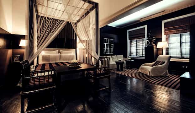 Rum med säng med sänghimmel, möbler och inredning i mörka färger. (AI-genererad text)