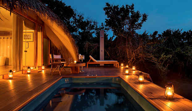 Avkopplande poolområde med tältliknande byggnad och stämningsfulla lyktor. (AI-genererad text)