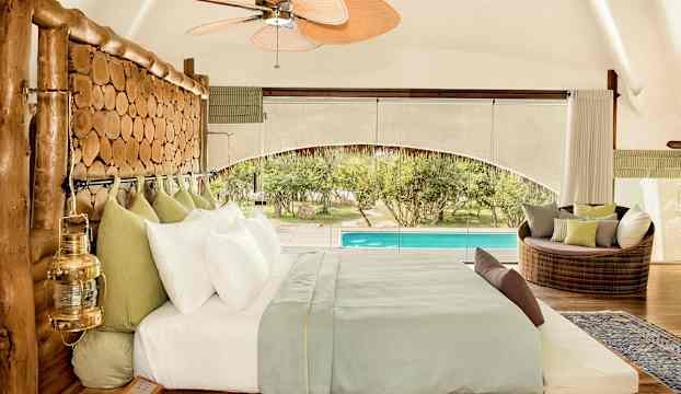 Ett välutrustat sovrum med en träinramad säng, stora fönster och utsikt över en pool. (AI-genererad text)