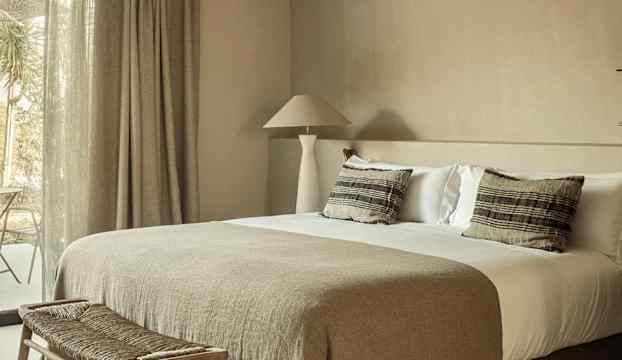 Ett sovrum med en stor säng och naturliga färger. (AI-genererad text)