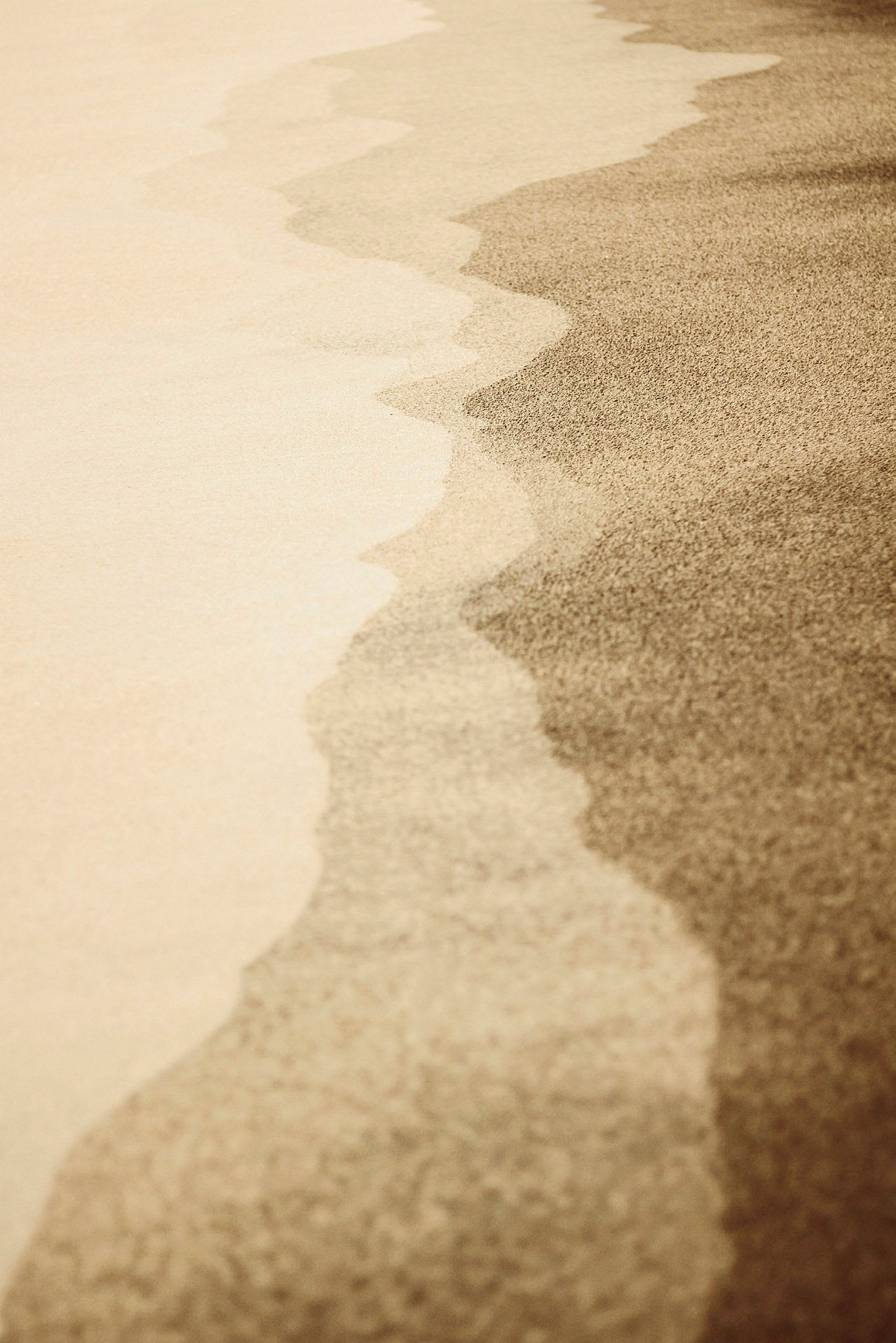 Närbild på en sandstrand med skuggade mönster. (AI-genererad text)