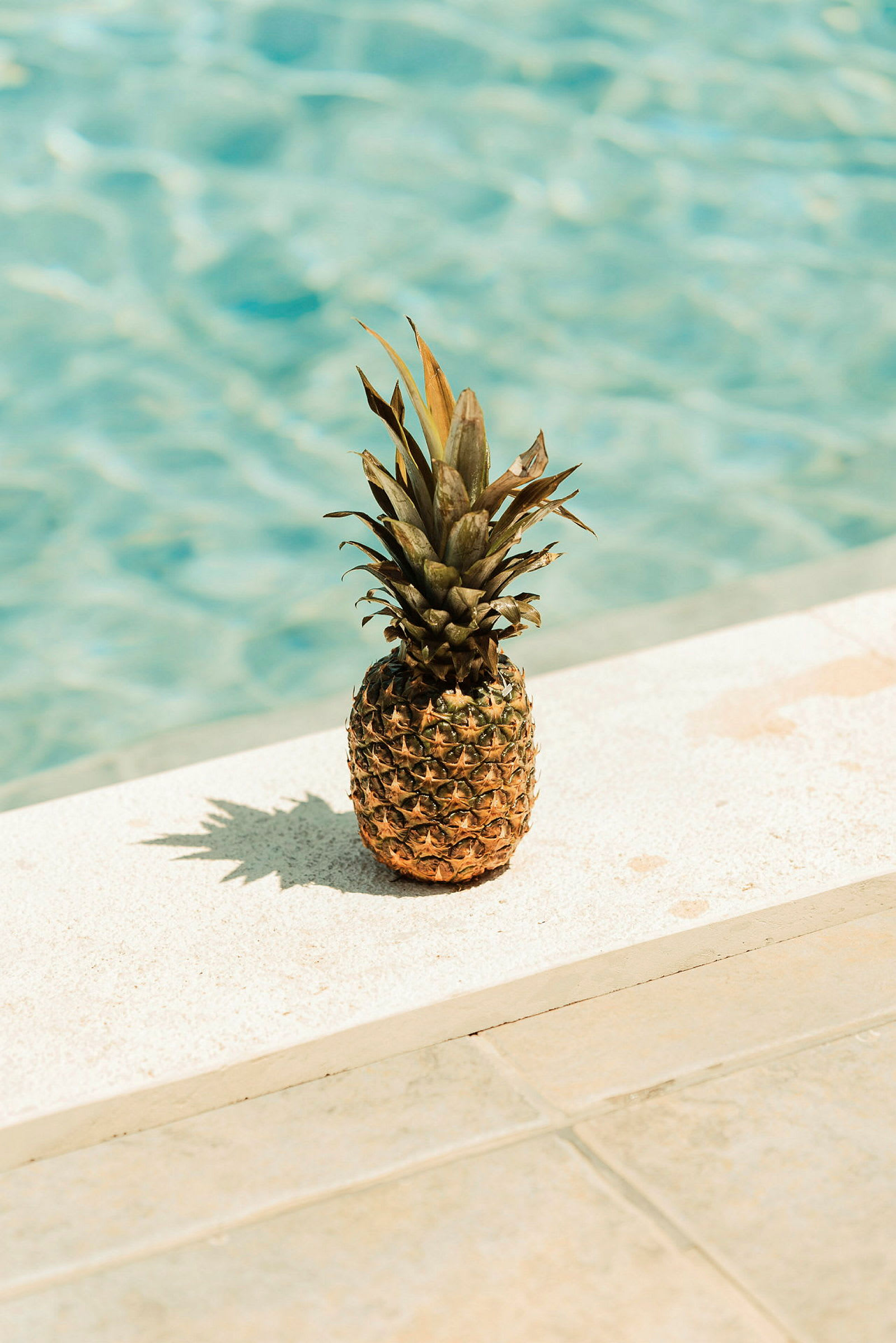 En ananas placerad på en kant vid poolen. (AI-genererad text)
