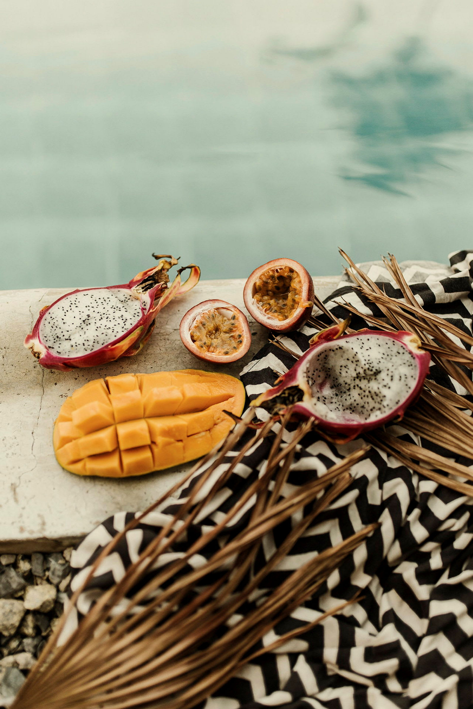 Exotiska frukter, inklusive mango, passionsfrukt och pitaya, ligger vid sidan av en pool. (AI-genererad text)
