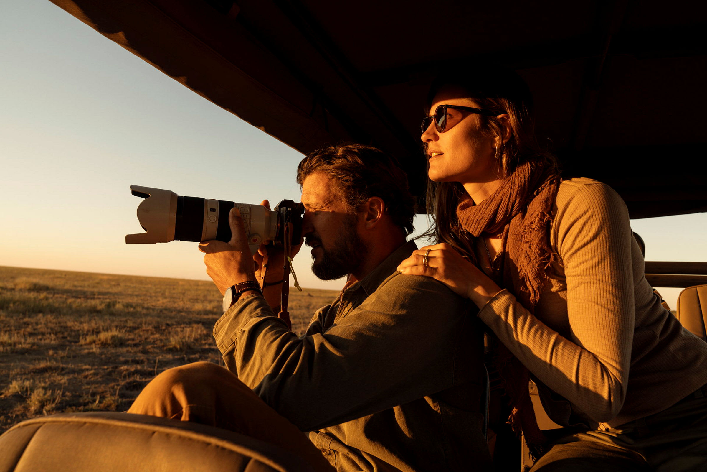 En person fotograferar med en kamera med stor lins, sittandes i en safaribil. (AI-genererad text)