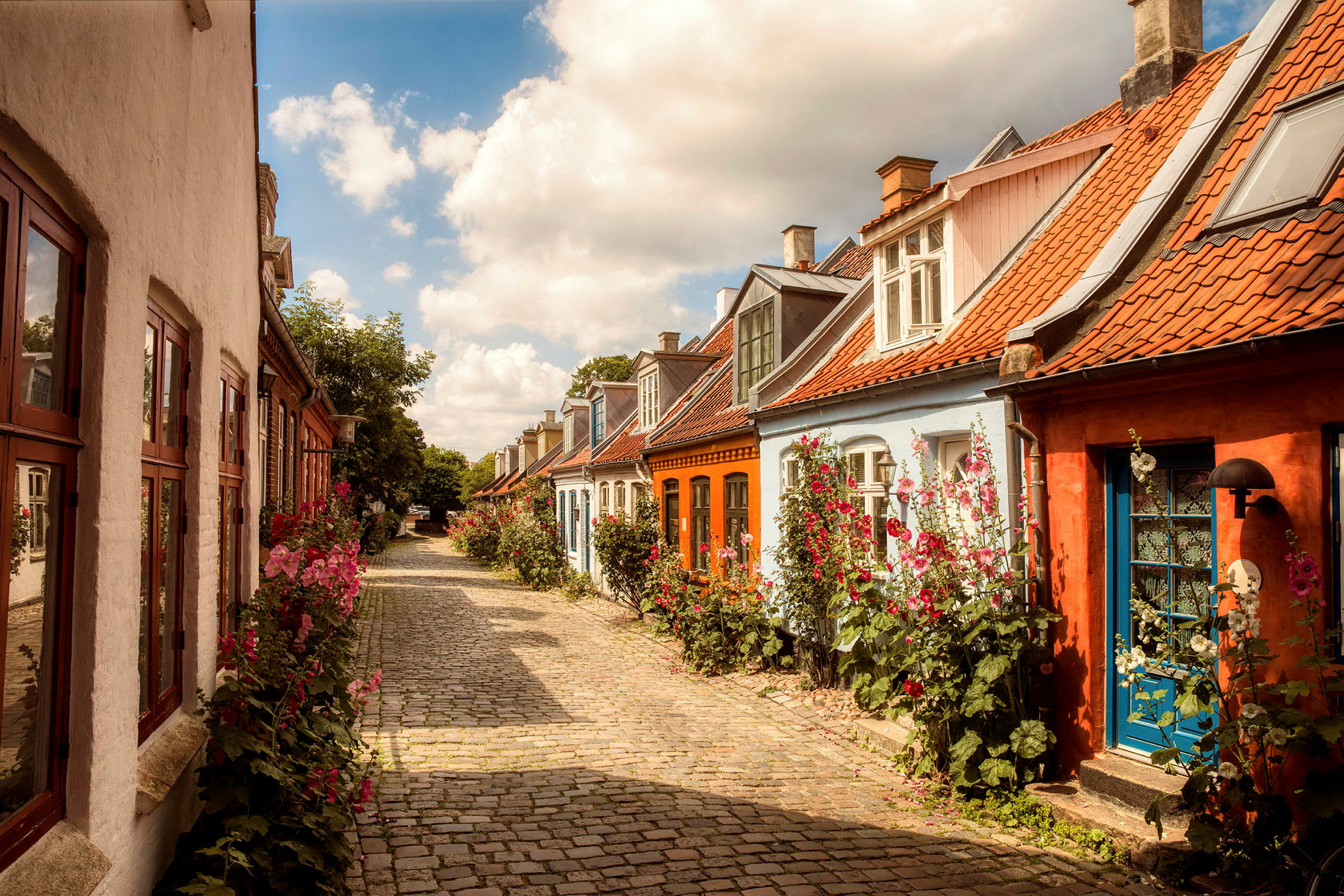 En gata med färgglada hus och blommor längs vägen. (AI-genererad text)