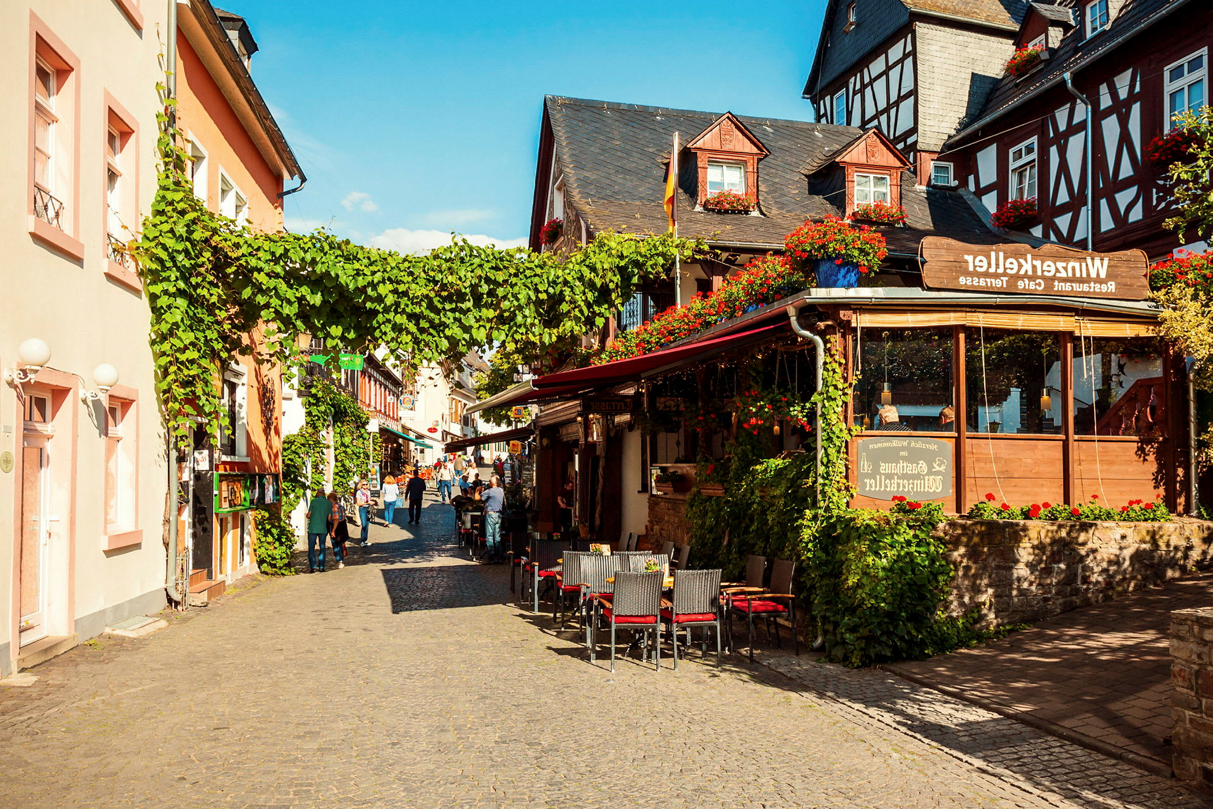 En pittoresk gata med restaurangförsedd uteservering och äldre arkitektur. (AI-genererad text)