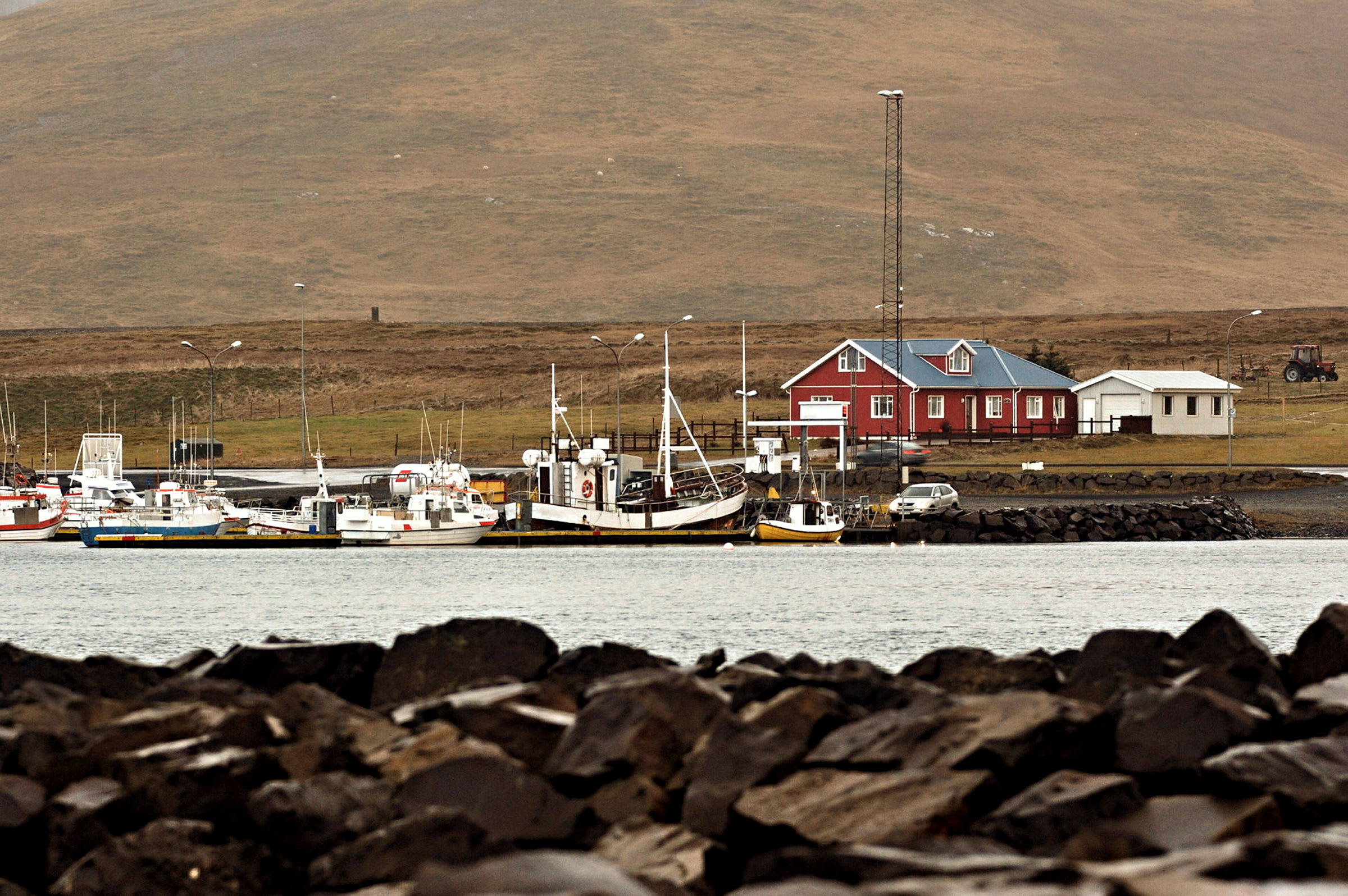 En hamn med båtar och ett rött hus i bakgrunden. (AI-genererad text)
