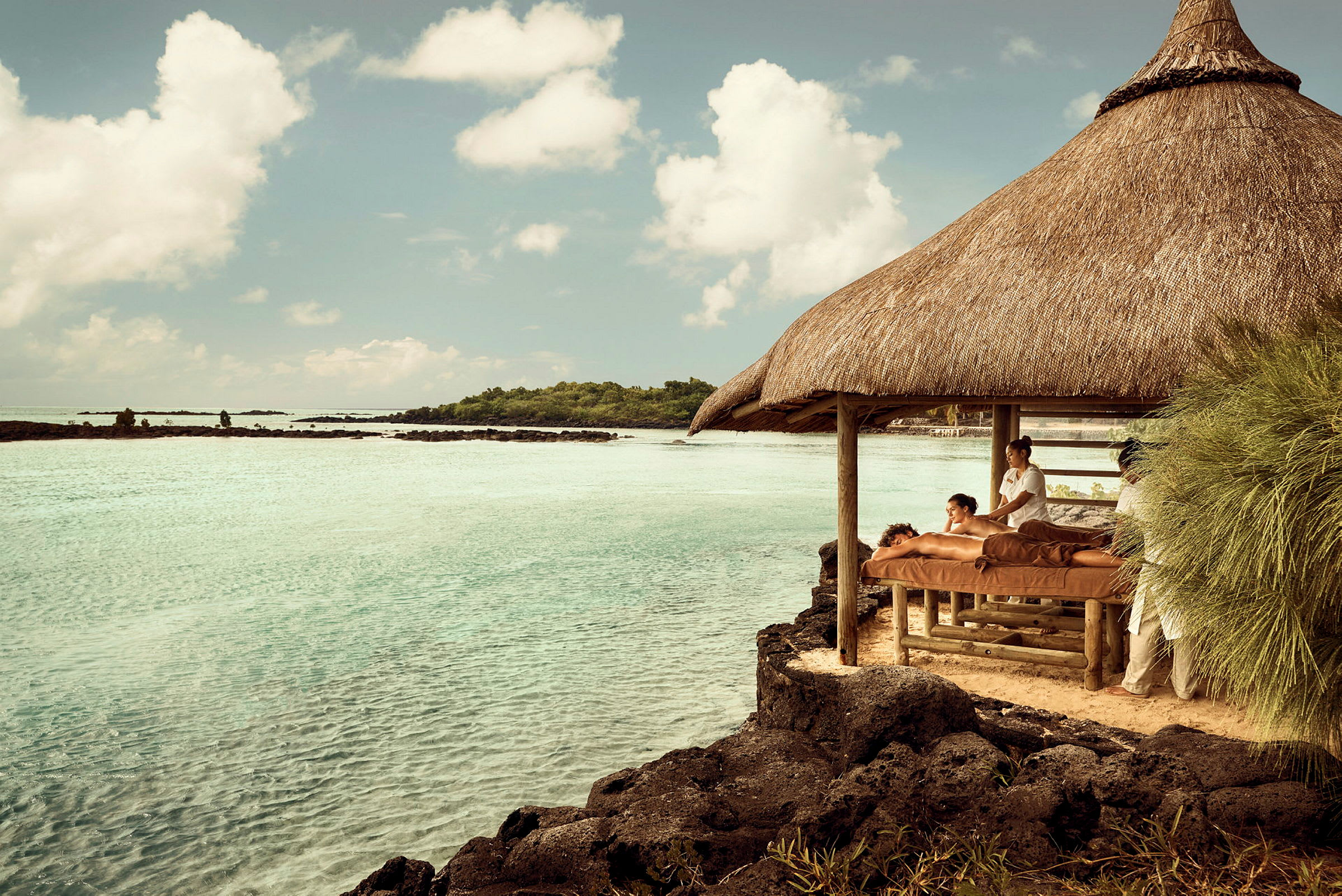 Person får massage under ett halmtak vid havet. (AI-genererad text)