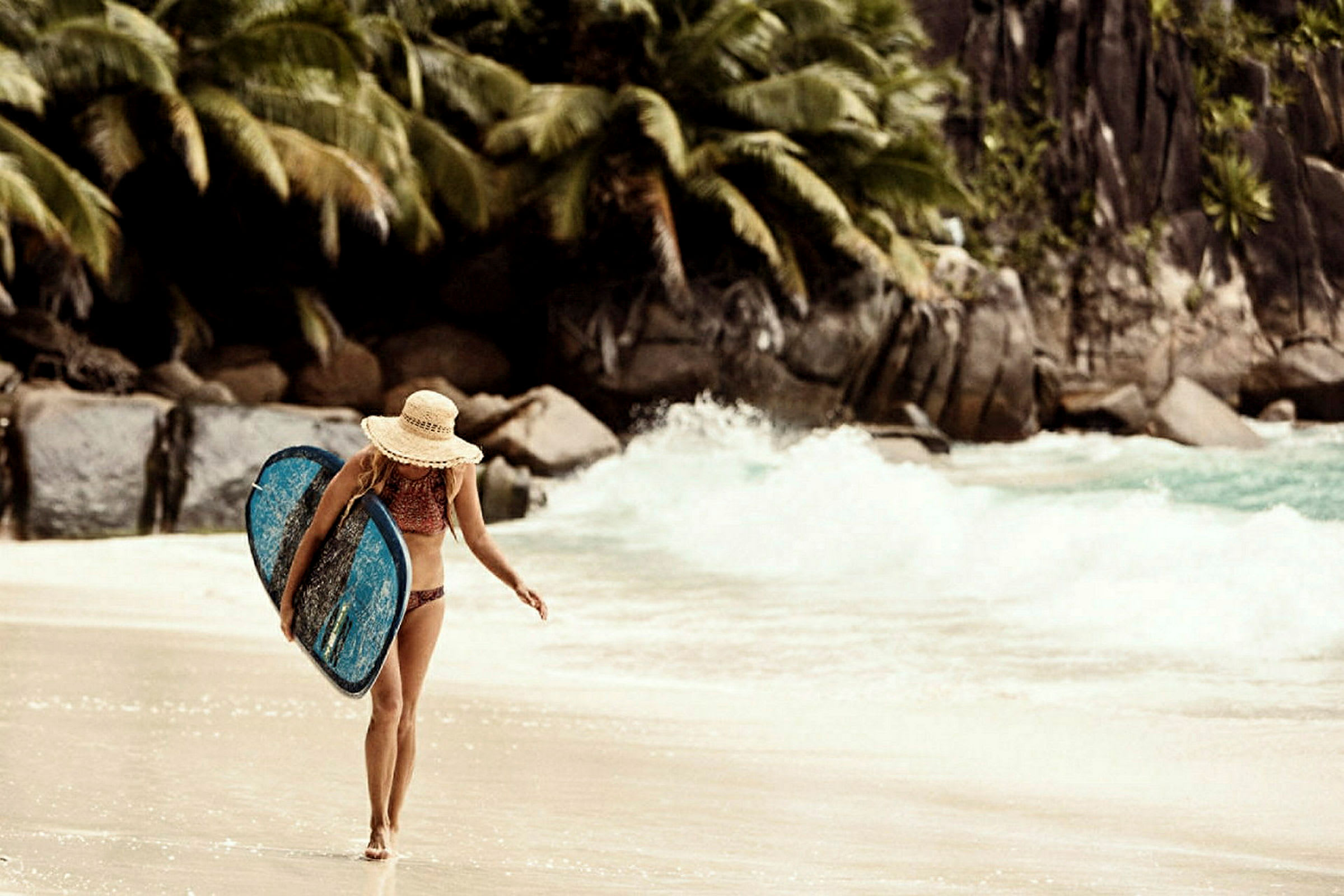 En person går på en strand och bär en surfingbräda. (AI-genererad text)