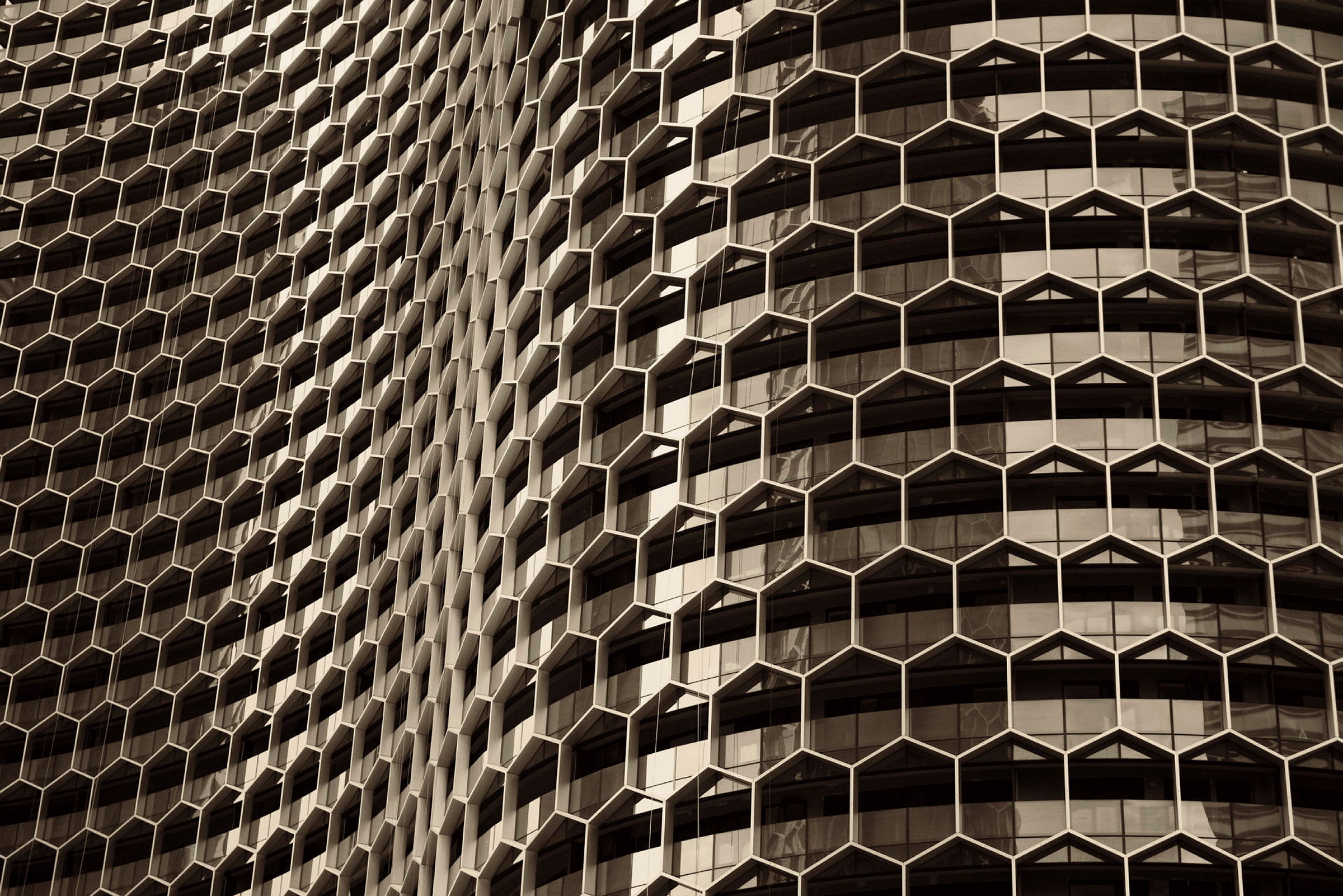 Fasad av en byggnad med regelbundet hexagonalt mönster och fönster. (AI-genererad text)