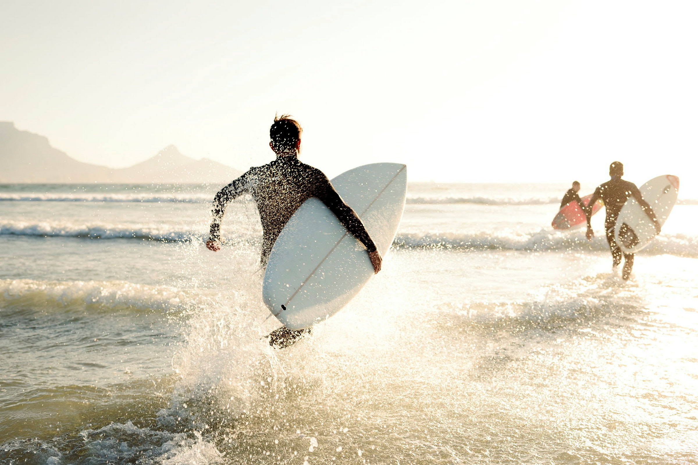 Personer med surfbrädor springer ut i havet. (AI-genererad text)