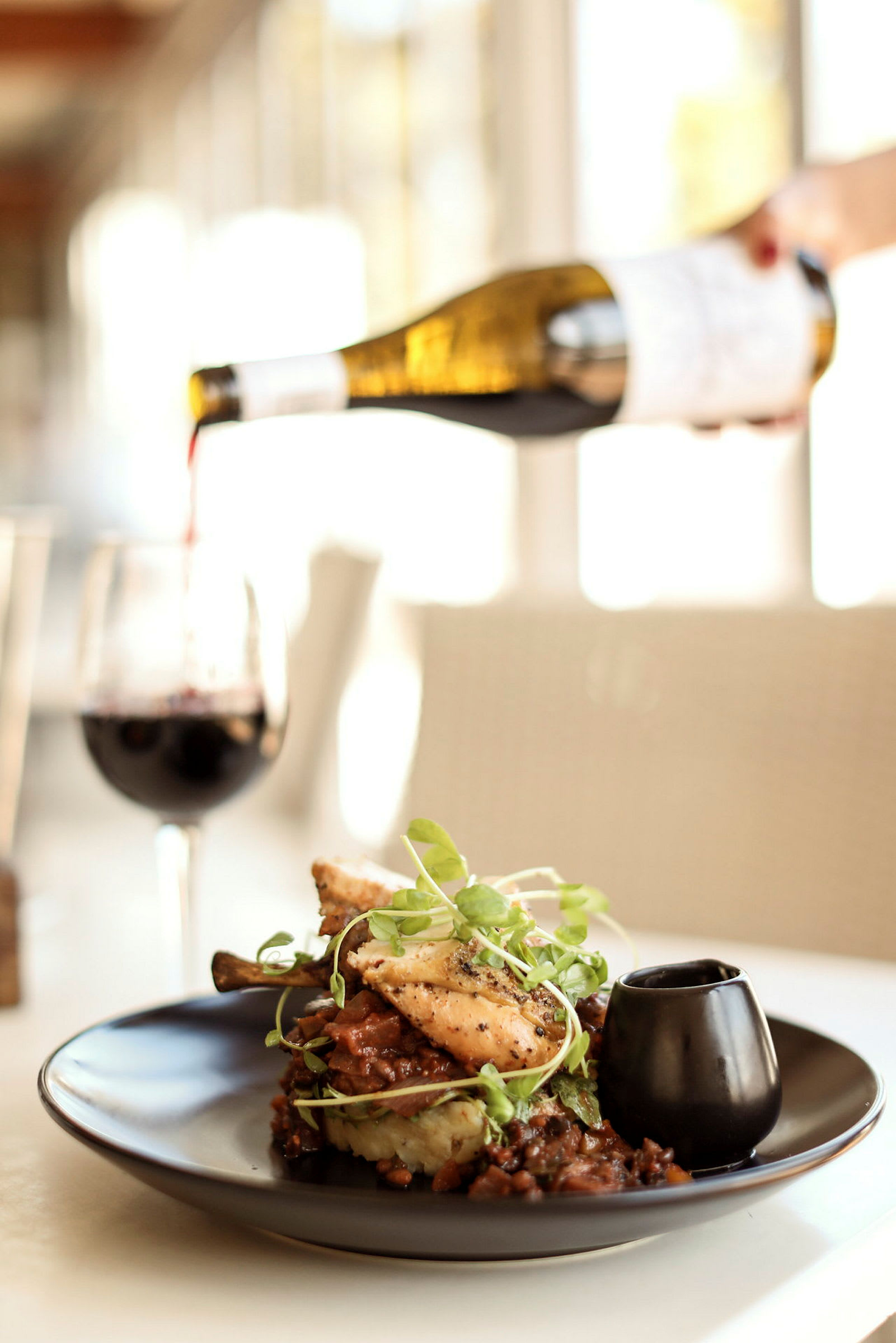 En maträtt serveras på en tallrik med ett glas rött vin bredvid. (AI-genererad text)