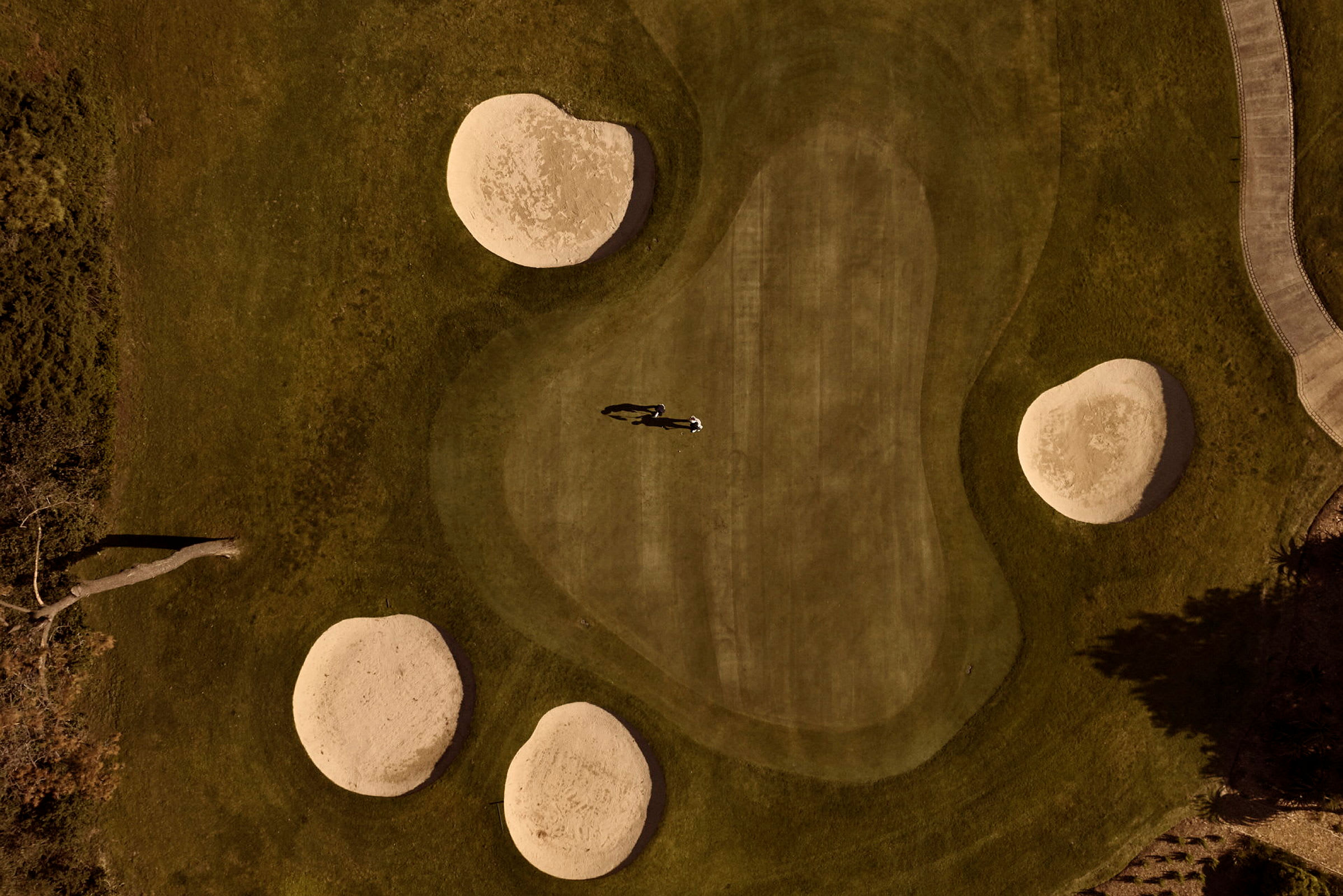 Flygfoto över en golfbana med sandbunkrar och grönområde. (AI-genererad text)