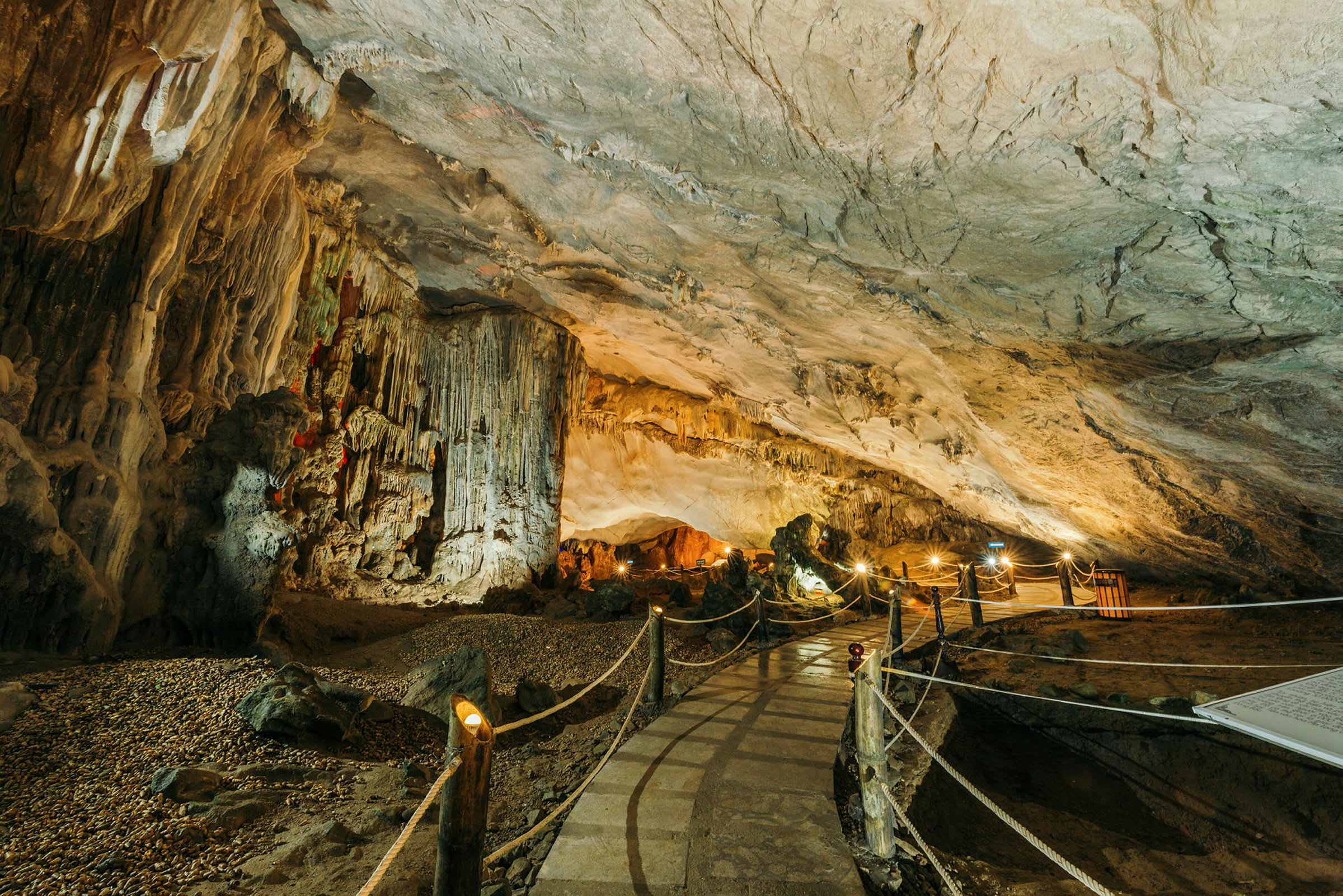En belyst grotta med stalaktiter och en gångväg omgiven av rep. (AI-genererad text)